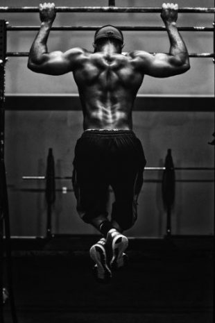Back & arms of a very muscular male athlete or boxer doing pull-ups. Improve sports performance & become the winner using RTT