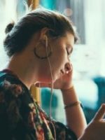 Woman listening with ear buds to her bespoke RTT transformational personalised audio – what to expect in a session, this is an important component of RTT Rapid Healing Therapy Process